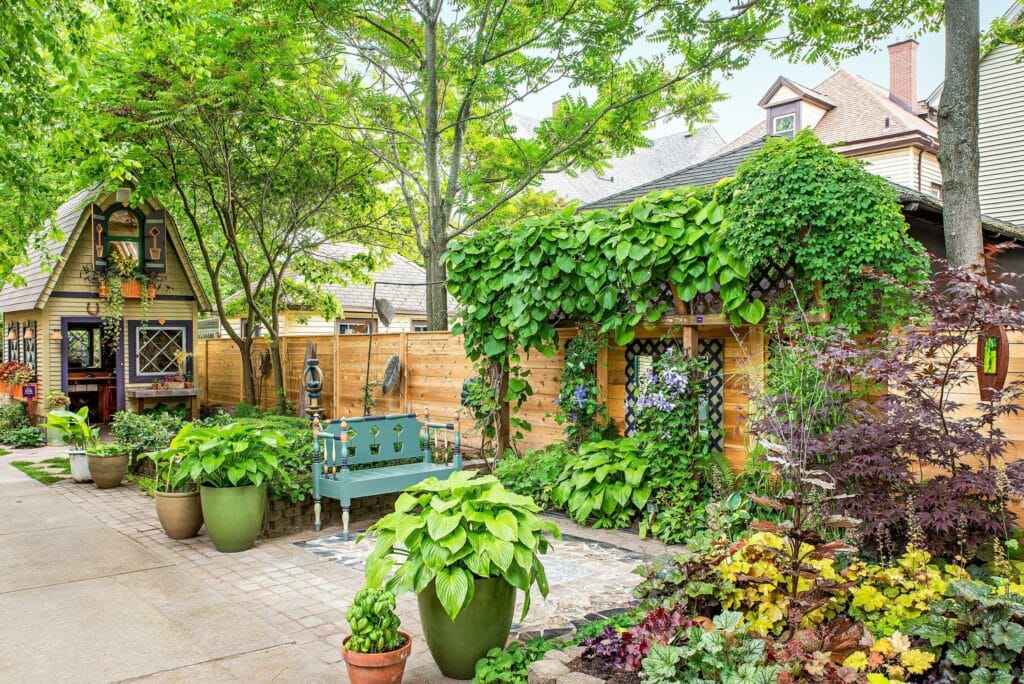 the courtyard space of a house with trees, beautiful plants and a small decorated cottage 