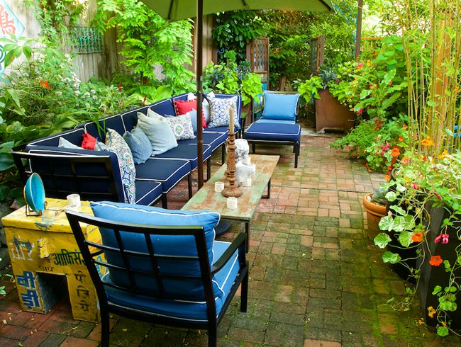 blue sofa set with plenty of flowers and plants in the outdoor space of a home