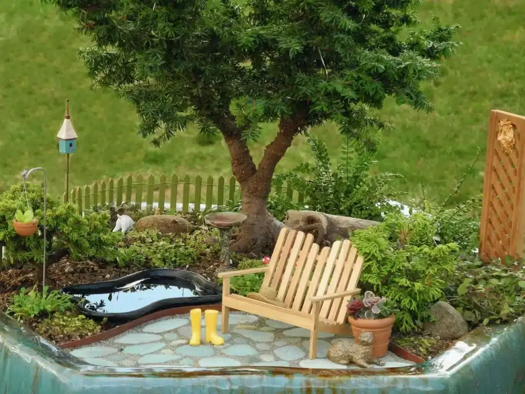 Miniature Garden in the courtyard of a house with wooden chair, water feature, tree and herbs 