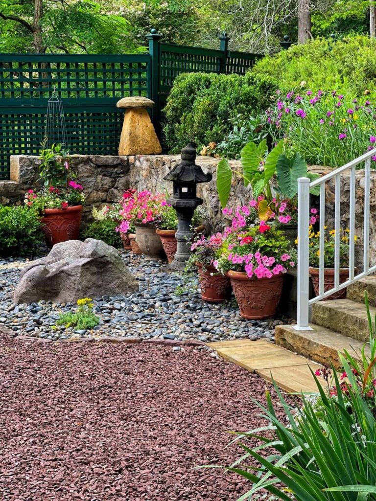  Zen garden with gravel, stones and colorful flowers in the backyard with stairs