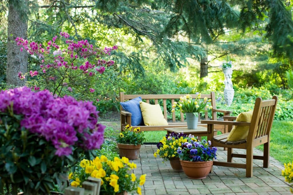 spring garden with flower pots, table and wooden chairs 