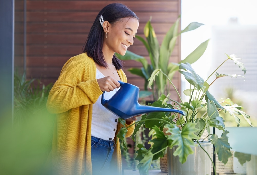 A view of a girl watering plants in her apartment balcony