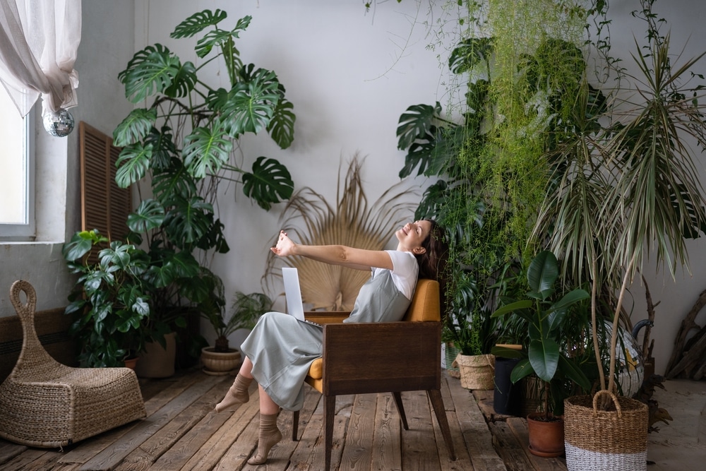 A view of a lady sitting inside an apartment gardening